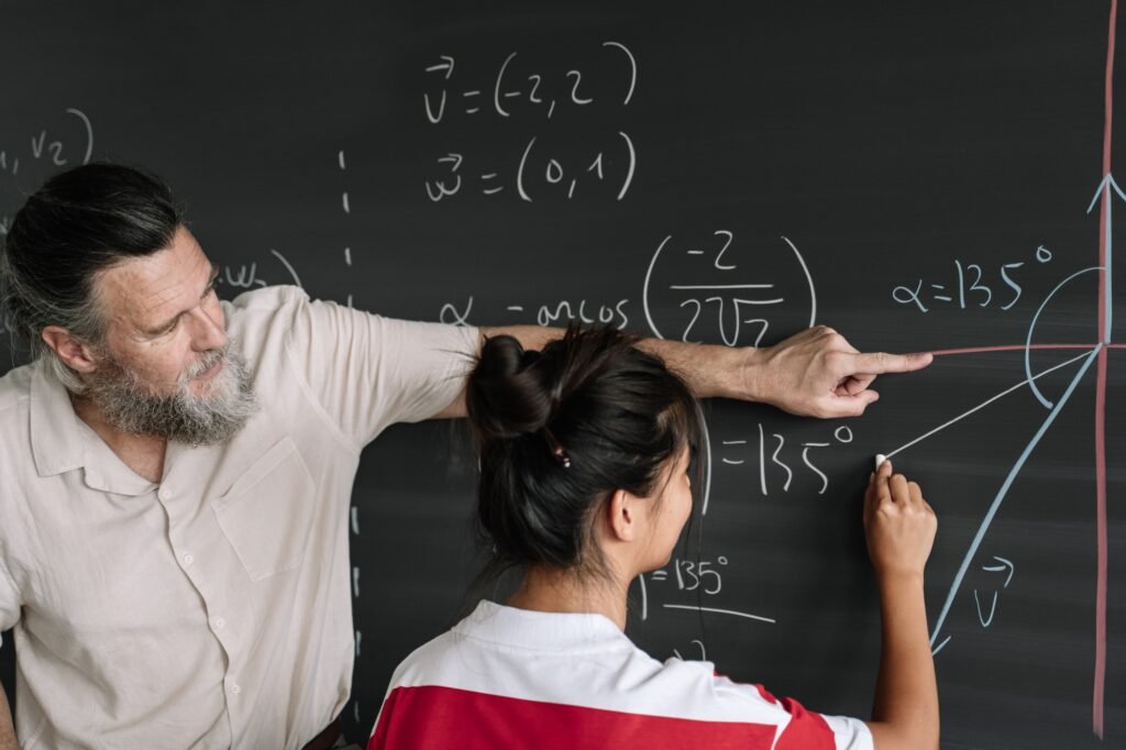 Asian Teenager Student doing Maths Exercises on Blackboard with teacher help in High School