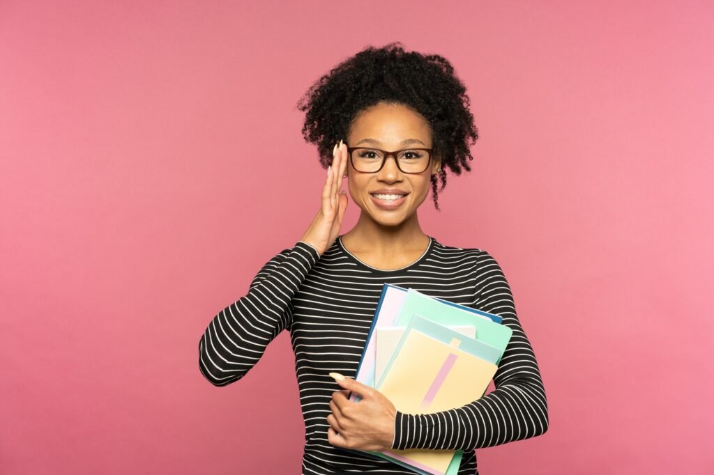 happy Afro-American tutor or teacher woman isolated on pink studio wall. Education in high school