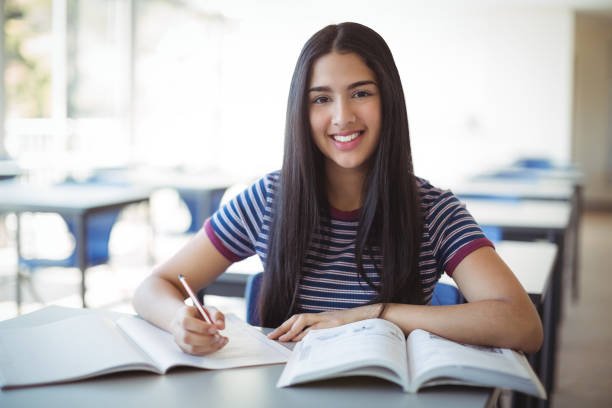 Schoolgirl doing homework in classroom at school
